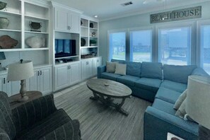 A living room with a blue sofa, a coffee table, and white cabinets. - Coastal duplex w multi-levels, shared pool and close to beach (Gulf Shores)