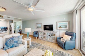 A living room with a ceiling fan, a TV, a cabinet, two sofas, and a dining area.
