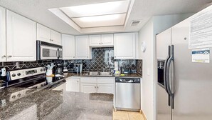 Een moderne keuken met dakraam, roestvrijstalen apparatuur en een vaatwasser.