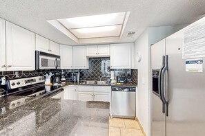 A modern kitchen with a skylight, stainless steel appliances, and a dishwasher.