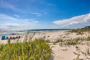 Ein Strand mit Dünen, einem klaren Himmel und einer entfernten Meeresansicht.