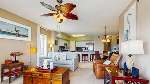 A spacious living area with a sofa, coffee table, and a ceiling fan. - Beachfront condo with shared pool, outdoor shower, and beach access (Gulf Shores)