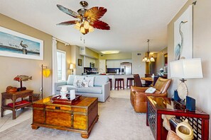 A spacious living area with a sofa, coffee table, and a ceiling fan. - Beachfront condo with shared pool, outdoor shower, and beach access (Gulf Shores)