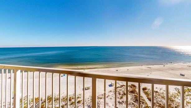 A beach view from a balcony with a railing, clear sky, and calm sea. - Dreamy beach condo with water views, balcony, pool & beach access (Orange Beach)