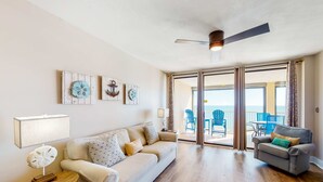 A living room with a sofa, a smaller couch, a side table, and a ceiling fan. - Dreamy beach condo with water views, balcony, pool & beach access (Orange Beach)