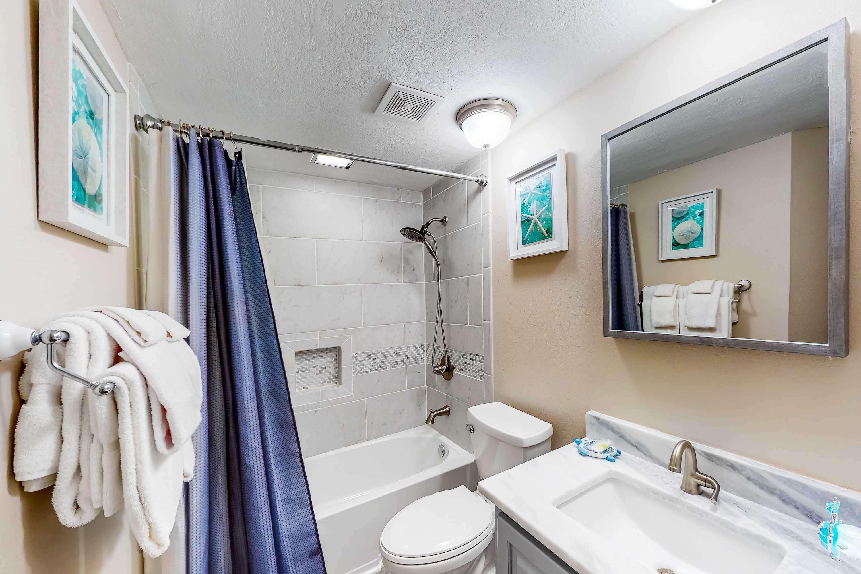 Une salle de bain équipée d’une baignoire, de toilettes et d’un lavabo, avec des serviettes suspendues à un porte-serviettes.