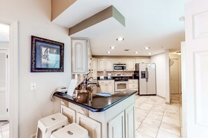 A kitchen with white cabinets, a built-in oven, a microwave, and a refrigerator. - Ninth-Floor Condo in Beachfront Resort with Free WiFi, Shared Pool, Tennis Court (Orange Beach)