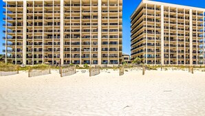 Ein Strandhotel mit mehreren Etagen, Balkonen und einem Sandstrand.