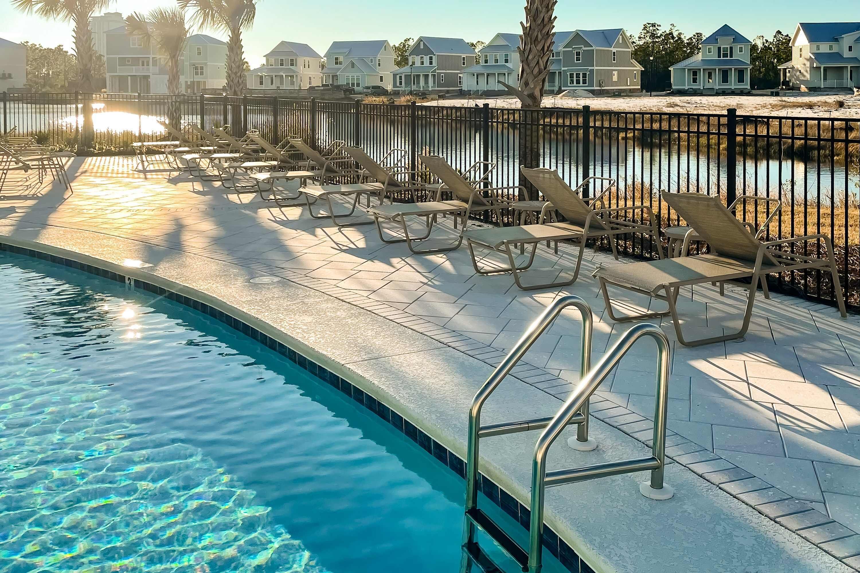A swimming pool with lounge chairs and a metal railing.