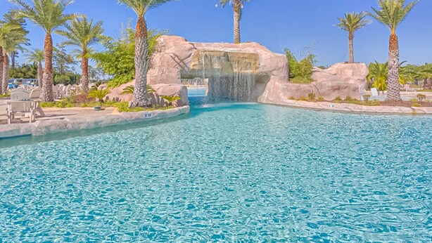 Ein Pool mit Wasserfall, Palmen und Liegestühlen.