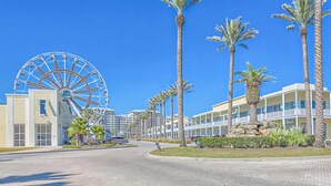 Ein Hotel mit einem großen Riesenrad, Palmen und einem gepflasterten Weg.