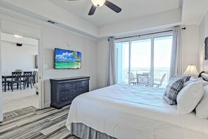 A hotel room with a bed, a television, a dresser, a balcony with a view, and a dining area. - Clean & spacious Canalfront condo with pool & hot tub on-site, gorgeous sunsets (Orange Beach)