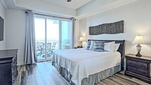 Ein Hotelzimmer mit einem Bett, zwei Nachttischlampen, einem Deckenventilator, einem großen Fenster mit Vorhängen und Blick ins Freie.