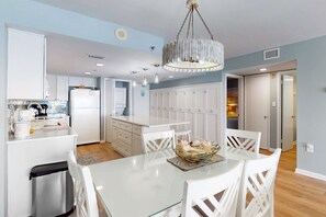 Une cuisine moderne avec des meubles blancs, un îlot central et un coin repas avec des chaises blanches.