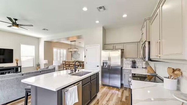 Una cocina moderna con una isla central, electrodomésticos de acero inoxidable y un comedor con candelabro.