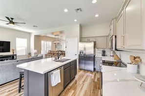 A modern kitchen with a central island, stainless steel appliances, and a dining area with a chandelier. - Surprise Getaway with Heated Pool Included! Close to Spring Training and Golf! (Surprise)