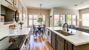 Una cocina moderna con una isla central, electrodomésticos integrados y ventanas amplias.