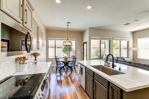 A modern kitchen with a central island, built-in appliances, and large windows. - Surprise Getaway with Heated Pool Included! Close to Spring Training and Golf! (Surprise)