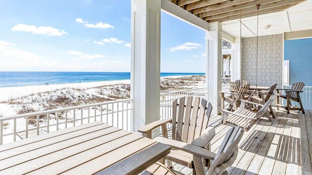 Eine Holterrasse mit Stühlen und Tischen mit Blick auf einen Strand.