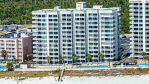 Un hotel di grattacielo con numerosi balconi, una piscina e vista sulla spiaggia.
