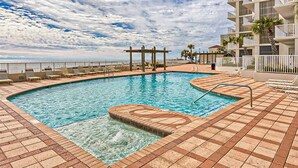 Una piscina con vista sull'oceano, un pergolato e un edificio a più piani con balconi.