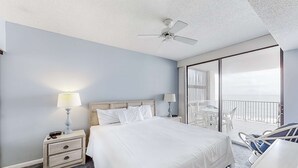 Una camera d'albergo con un letto, comodini, una ventola a soffitto e un balcone con mobili da esterno.
