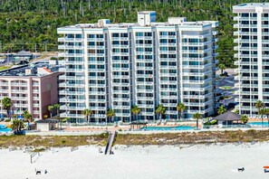 A high-rise hotel with multiple balconies, a swimming pool, and a beach view. - Beachfront condo with pool, tennis court, hot tub & central AC (Orange Beach)