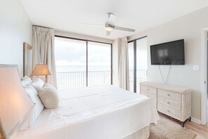 A hotel room with a bed, a television, a ceiling fan, and a view of the ocean. - Beachfront condo with pool, tennis court, hot tub & central AC (Orange Beach)