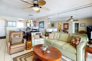 Ein Wohnzimmer mit Sofa, Sessel, Couchtisch und Deckenventilator.