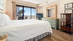 Une chambre d’hôtel avec un grand lit, une télévision, une commode et un balcon avec vue.