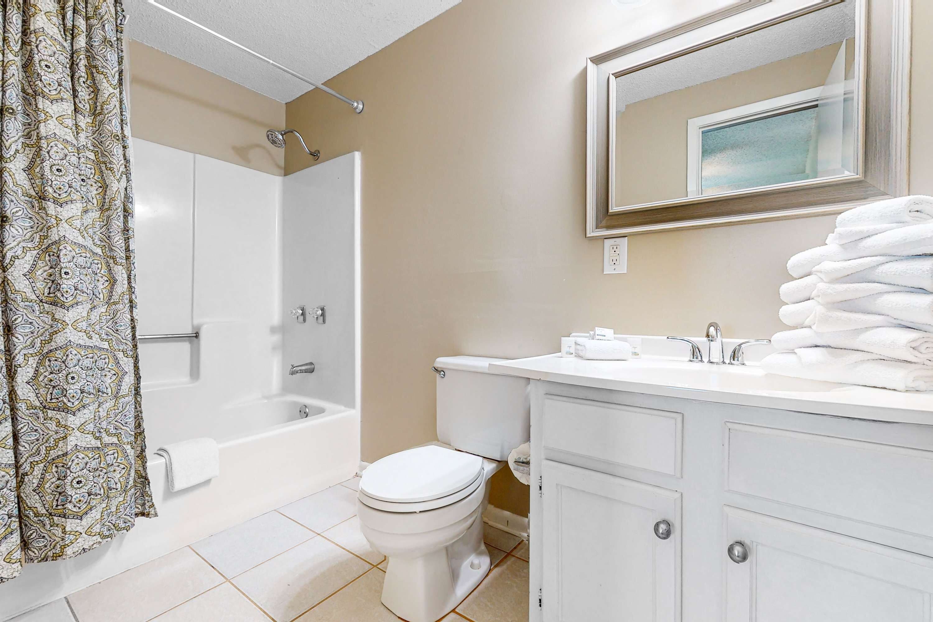 Et badeværelse med badekar, toilet og vaskebord med spejl.