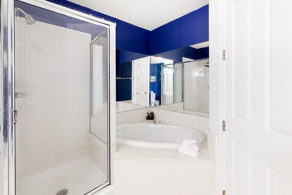 A bathroom with a glass-enclosed shower, a white bathtub, and a large mirror. - Gulf-front condo with shaded balcony, pools, hot tubs, gym & beach access (Orange Beach)