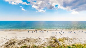 A beach with umbrellas and a wooden walkway. - Gulf-front condo with shaded balcony, pools, hot tubs, gym & beach access (Orange Beach)