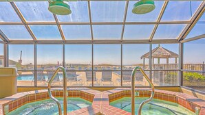Un espace jacuzzi clos par des parois de verre, offrant une vue dégagée sur la piscine et agrémenté d’un gazebo en arrière-plan.