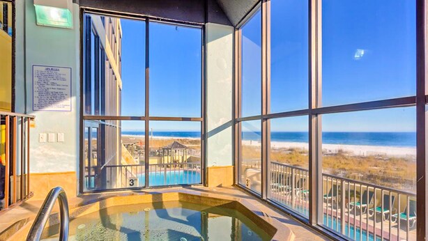 Ein Zimmer mit großem Fenster, einer Whirlpool-Badewanne und Blick auf den Strand.