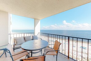 A balcony with a round table and chairs, a view of the beach, and a railing. - Beachfront condo with Gulf views, balcony, pool, hot tub, sauna & gym (Orange Beach)