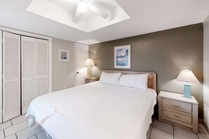 Un dormitorio con cama, dos lámparas de mesita de noche, ventilador de techo, mesita y armario.