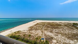 A beach with a clear sky, a sandy shore, and a pathway leading to a structure. - Gulf-front condo with inviting balcony, amazing views, pool & hot tub (Orange Beach)