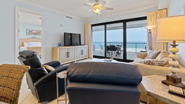 A modern living room with a sofa, a recliner, a TV, and a balcony with a view. - Gulf-front condo with inviting balcony, amazing views, pool & hot tub (Orange Beach)