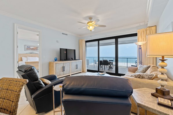 A modern living room with a sofa, a recliner, a TV, and a balcony with a view. - Gulf-front condo with inviting balcony, amazing views, pool & hot tub (Orange Beach)