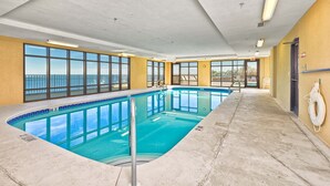 En inomhuspool med fri utsikt över havet, en livboj på väggen och en dörr som leder till ett annat område.