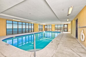 An indoor swimming pool with clear views of the ocean, a lifebuoy on the wall, and a door leading to another area. - 4th-floor Gulf-front condo with balcony, pool, hot tub, sauna & gym (Orange Beach)