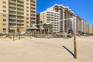 Une plage avec un filet de volley-ball, un poteau en bois et une petite cabane.