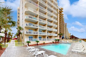 A multi-story hotel with a swimming pool, white railings, and palm trees. - Gulf & Beachfront Condo wBalcony, Central AC, Shared Hot Tub, Pools, Free WiFi (Orange Beach)