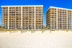 Ein Strandhotel mit mehreren Etagen, Balkonen und einem Sandstrand.
