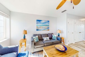 Ein Wohnzimmer mit einer Couch, zwei Beistelltischen, einem Couchtisch und einem Gemälde an der Wand.