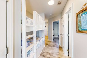 A hallway with bunk beds, a framed certificate on the wall, and a door leading to another room. - Spacious condo across from the beach with Gulf/bay views & a pool (Orange Beach)