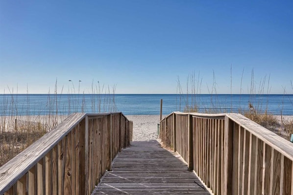 Un muelle de madera que lleva a una playa con cielos despejados.