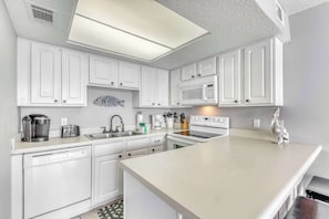 A modern kitchen with white cabinets, a dishwasher, a microwave, and a stove. - Gulf front condo with great views, shared pools & beach access (Orange Beach)