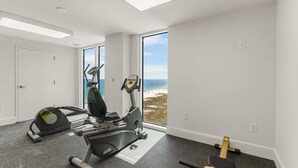 Une salle de sport équipée d’appareils de cardio, d’un rameur et d’un banc de musculation.